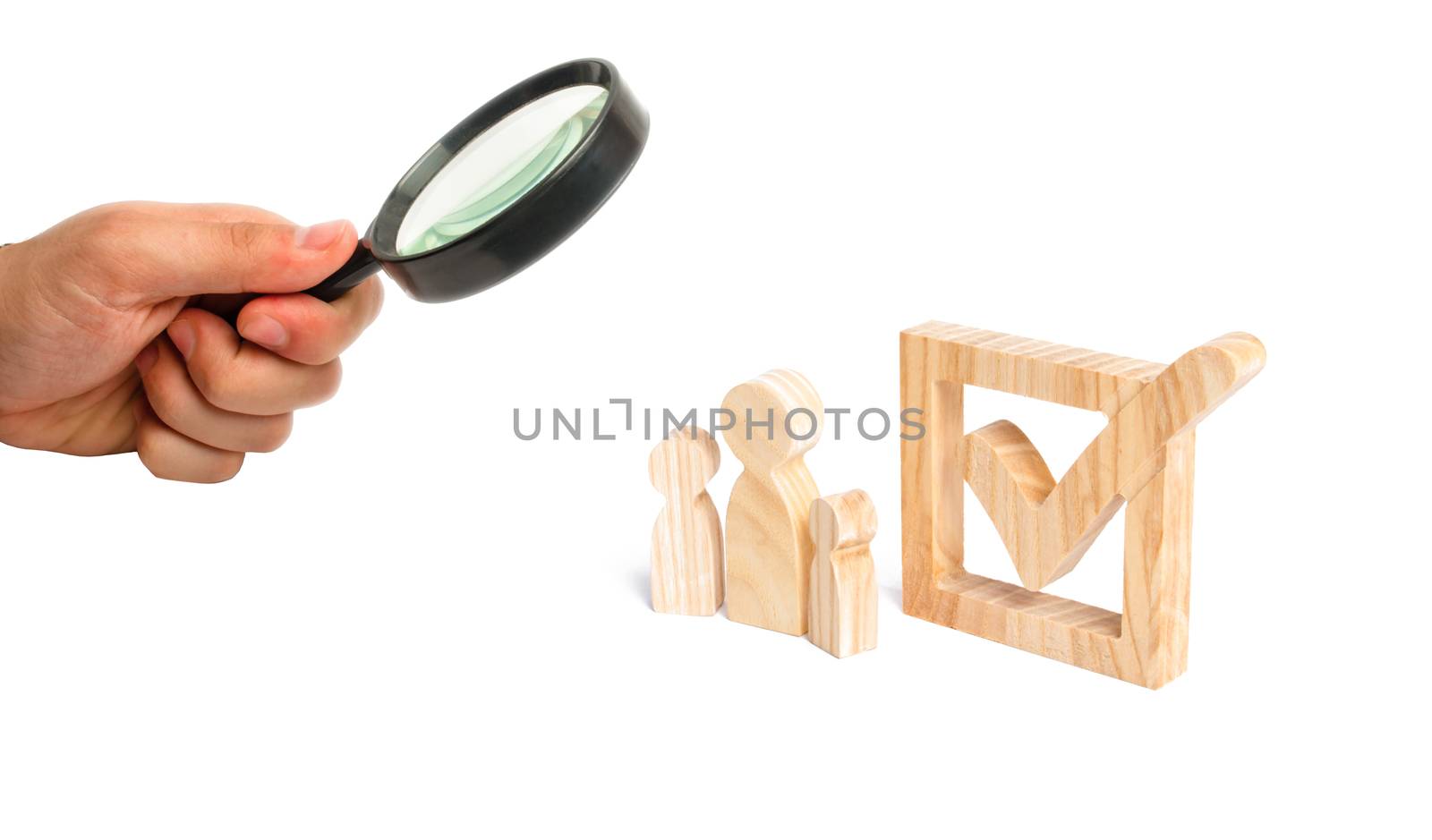 Magnifying glass is looking at the Three wooden human figures stand together next to a tick in the box. Volunteers, parties, candidates. Human rights. The concept of elections and social technologies.