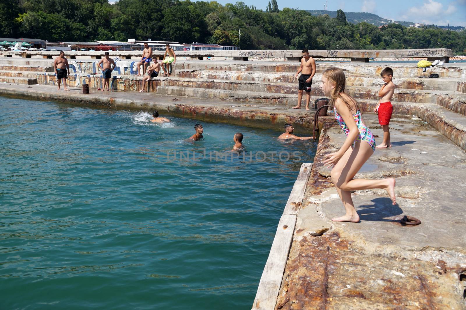 Varna, Bulgaria - July, 19, 2020: children jump into the sea from the pier