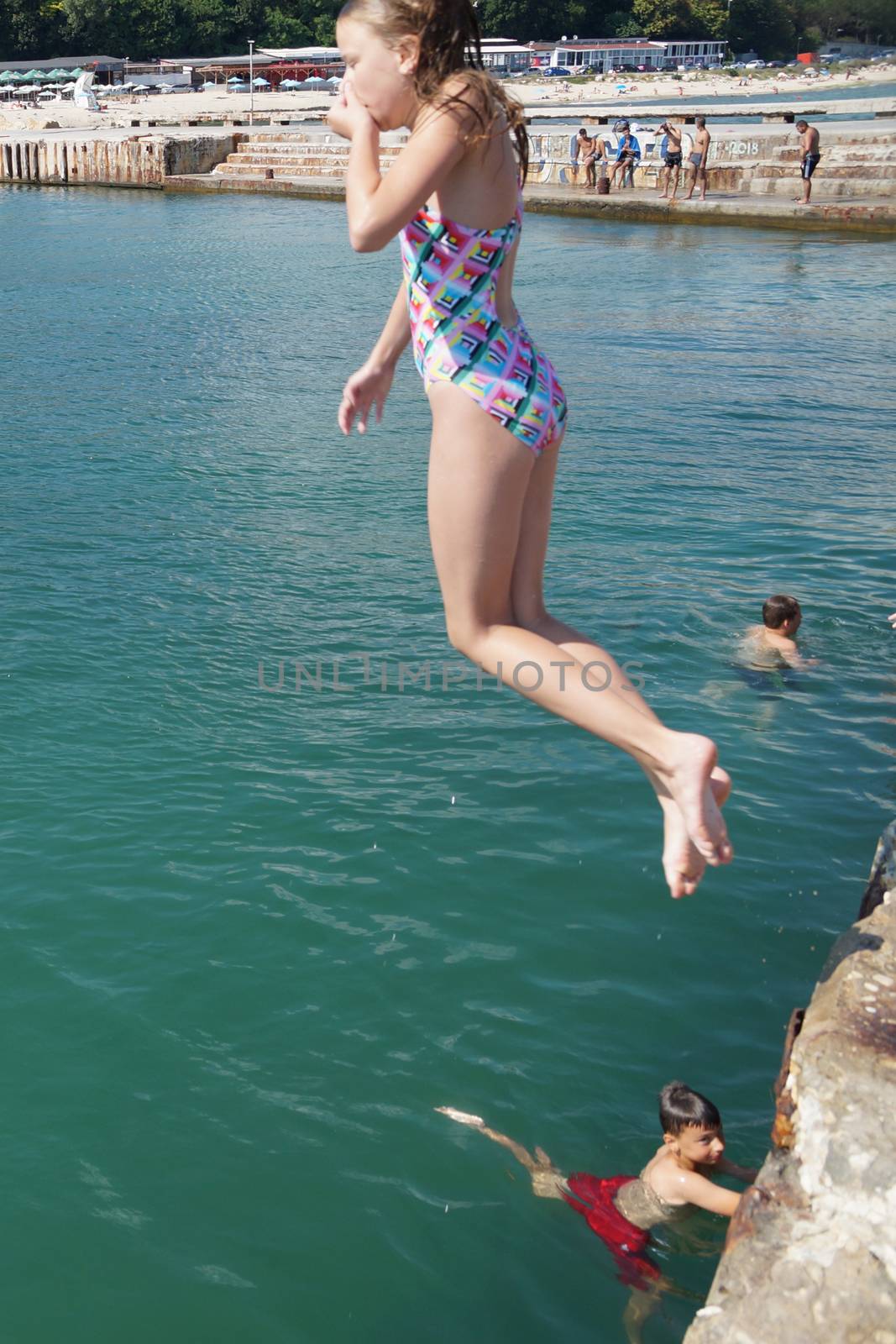 Varna, Bulgaria - July, 19, 2020: girl jumping into the sea from the pier.