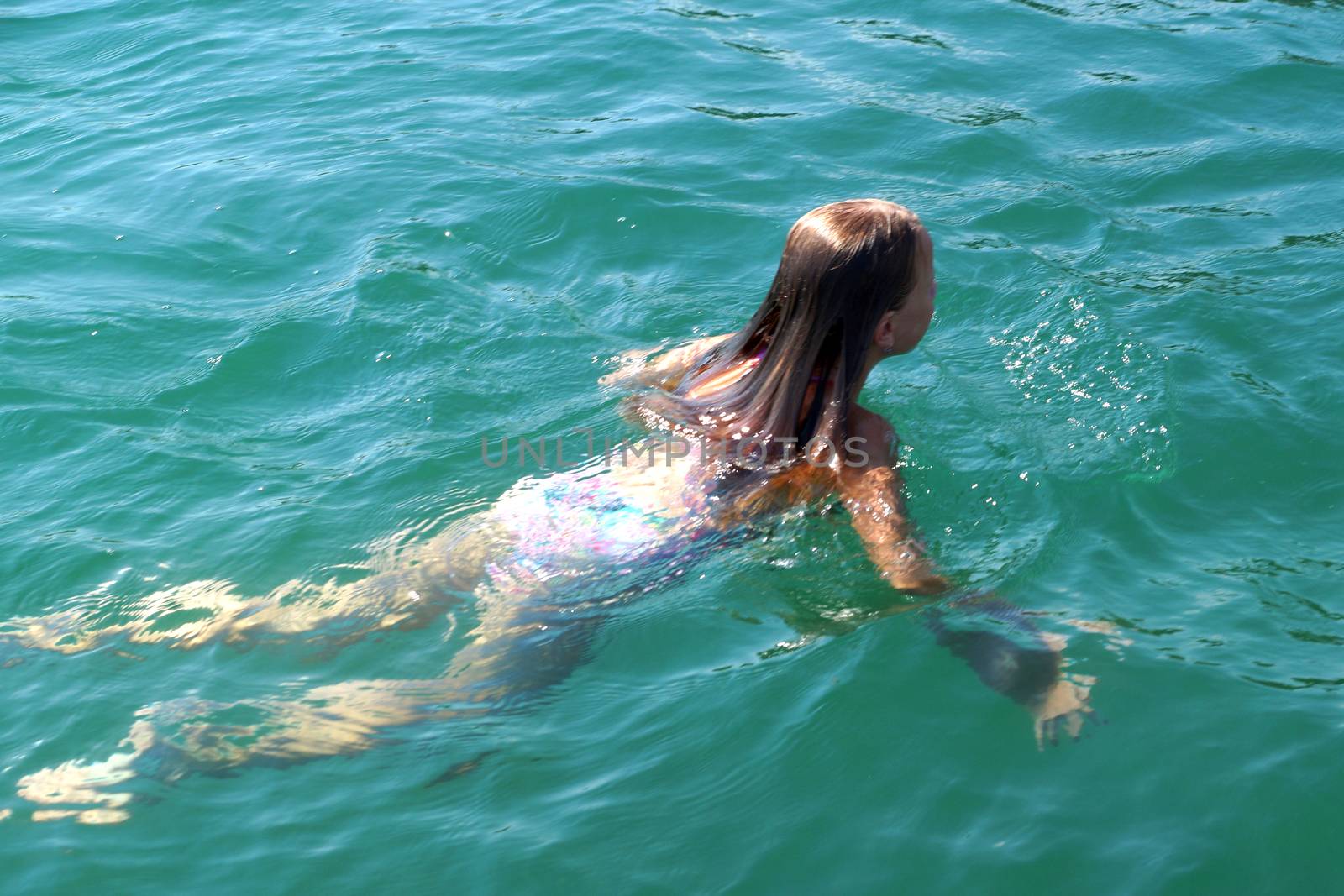 girl swims in the sea, back view