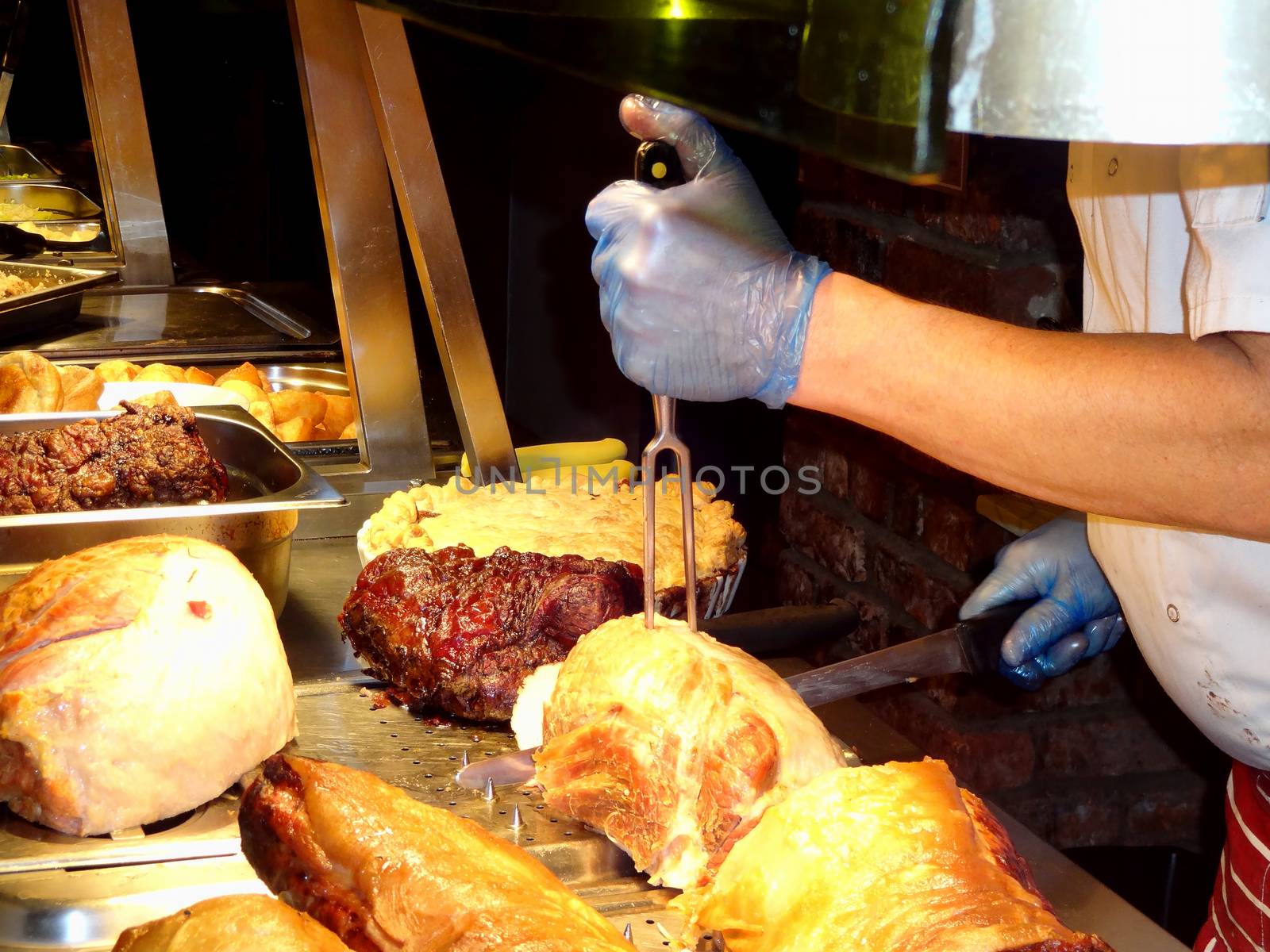 Chef carving roast beef and other meats at a buffet carvery stock photo                        