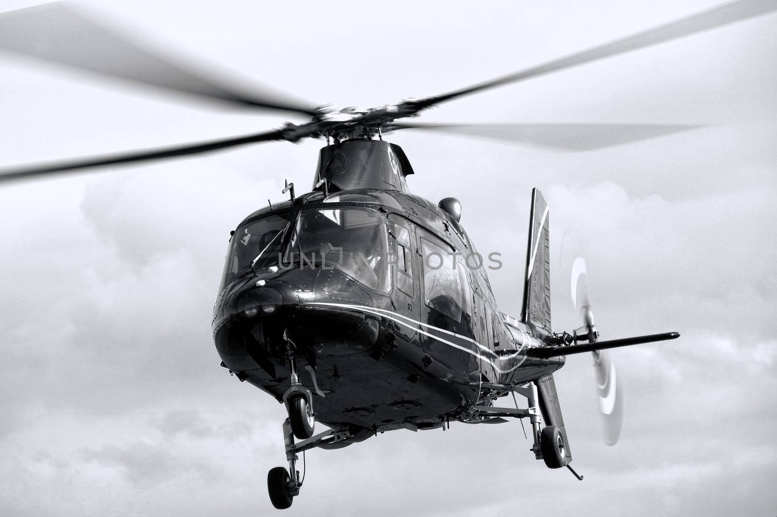 Helicopter aiplane hovering in flight with its blades rotating black and white monochrome image stock photo