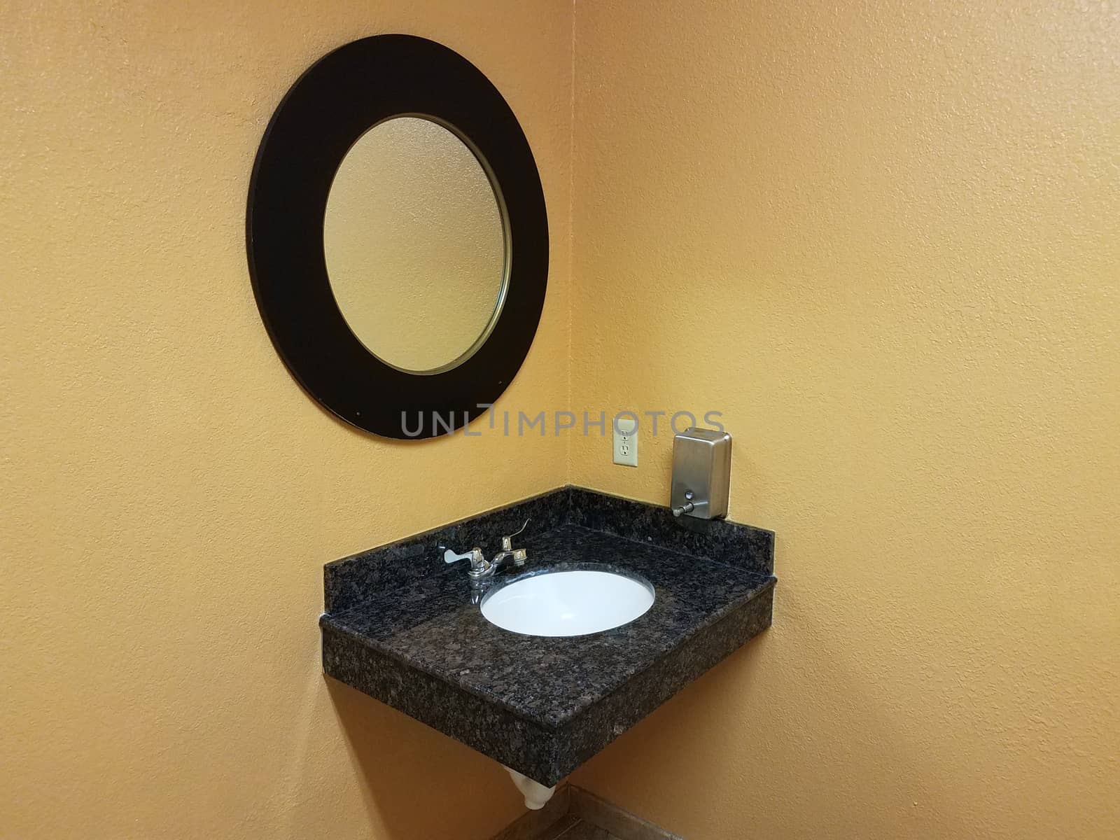 yellow wall in restroom or bathroom with sink and circular mirror