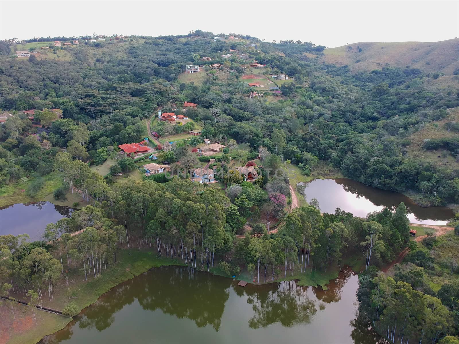 Aerial View of green scenic forest and land in the mountain in tropical country. Aerial view of forest to make with farm field and villa. Green area in the forest with lake