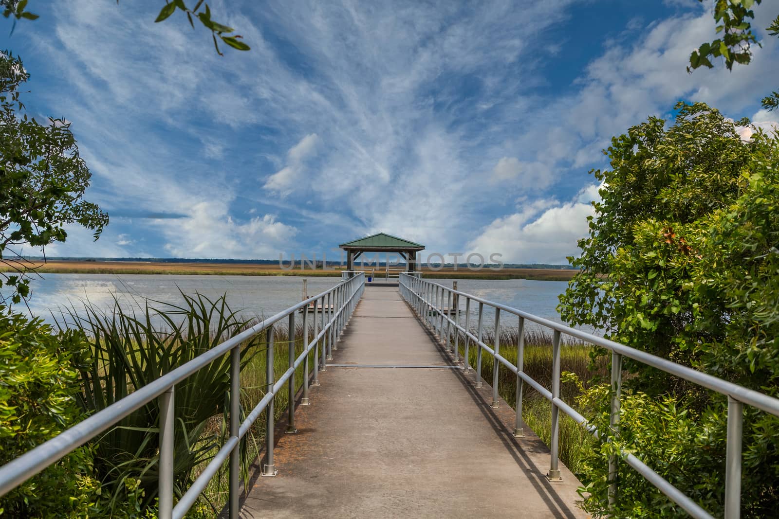An empty fishing pier heading out into a saltland marsh
