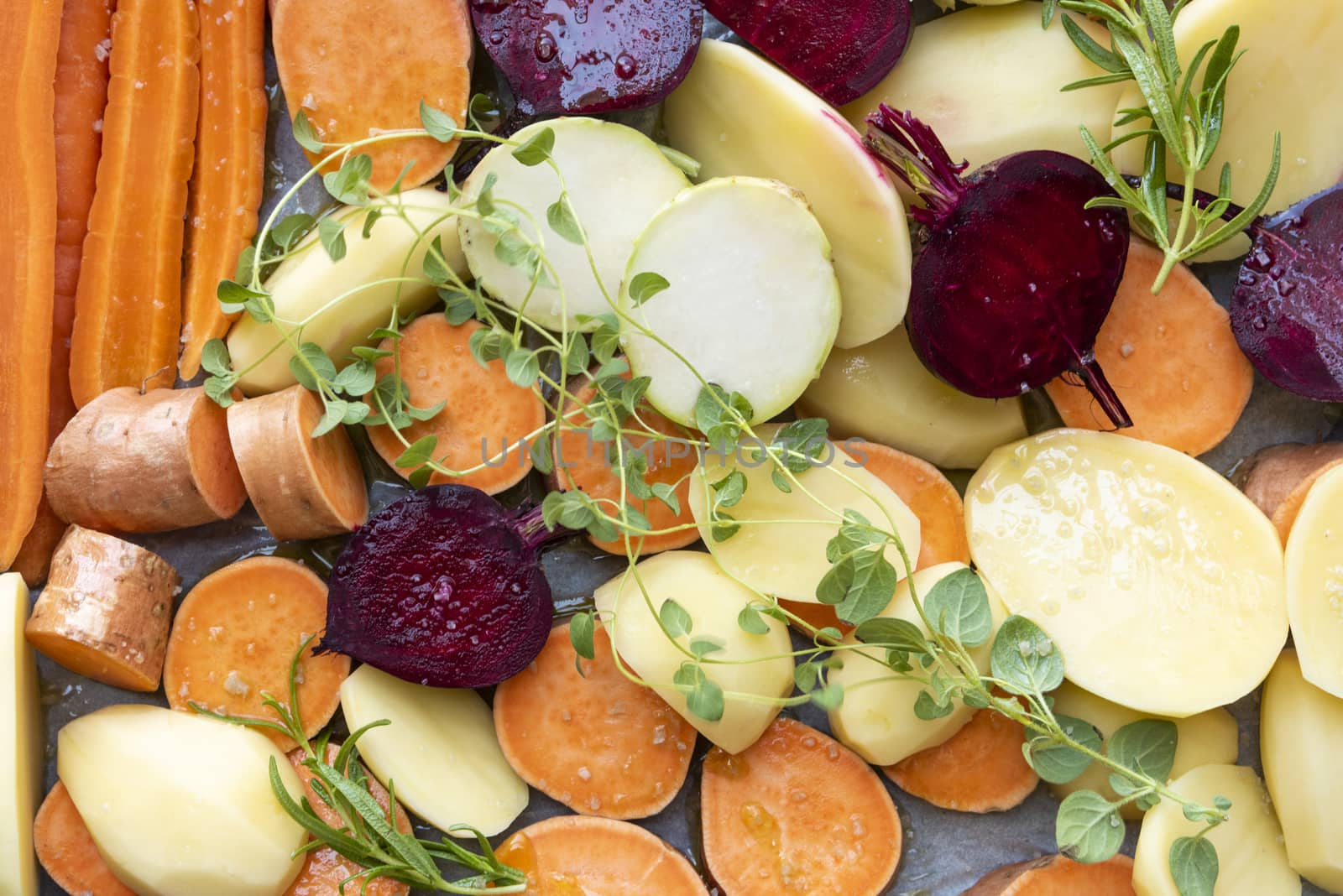 Cut raw vegetables before putting them in the oven. Carrots, potatoes, sweet potatoes, beets, kohlrabi, rosemary, garlic, hyssop