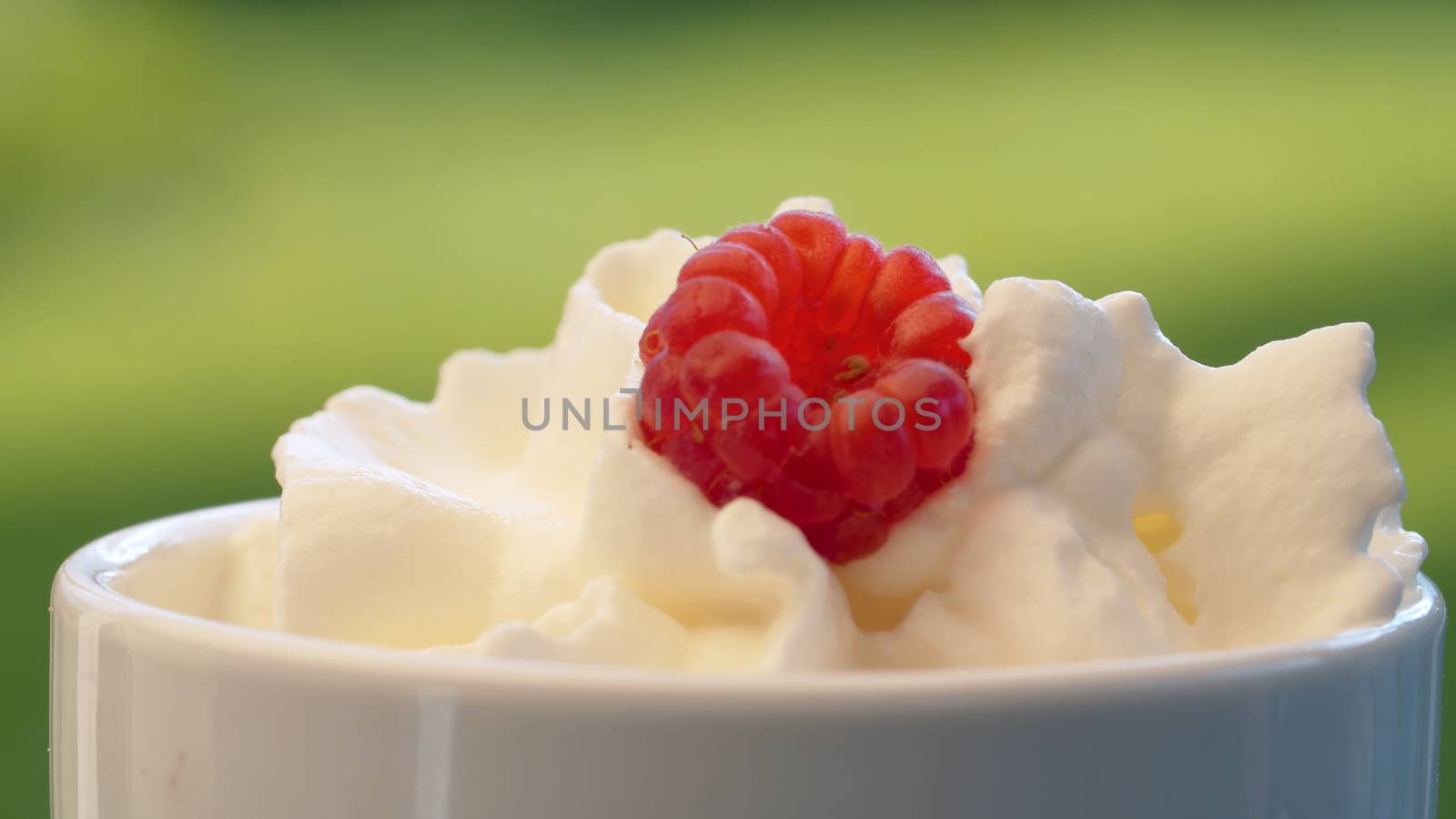 Whipped cream and raspberry in a cup by Alize