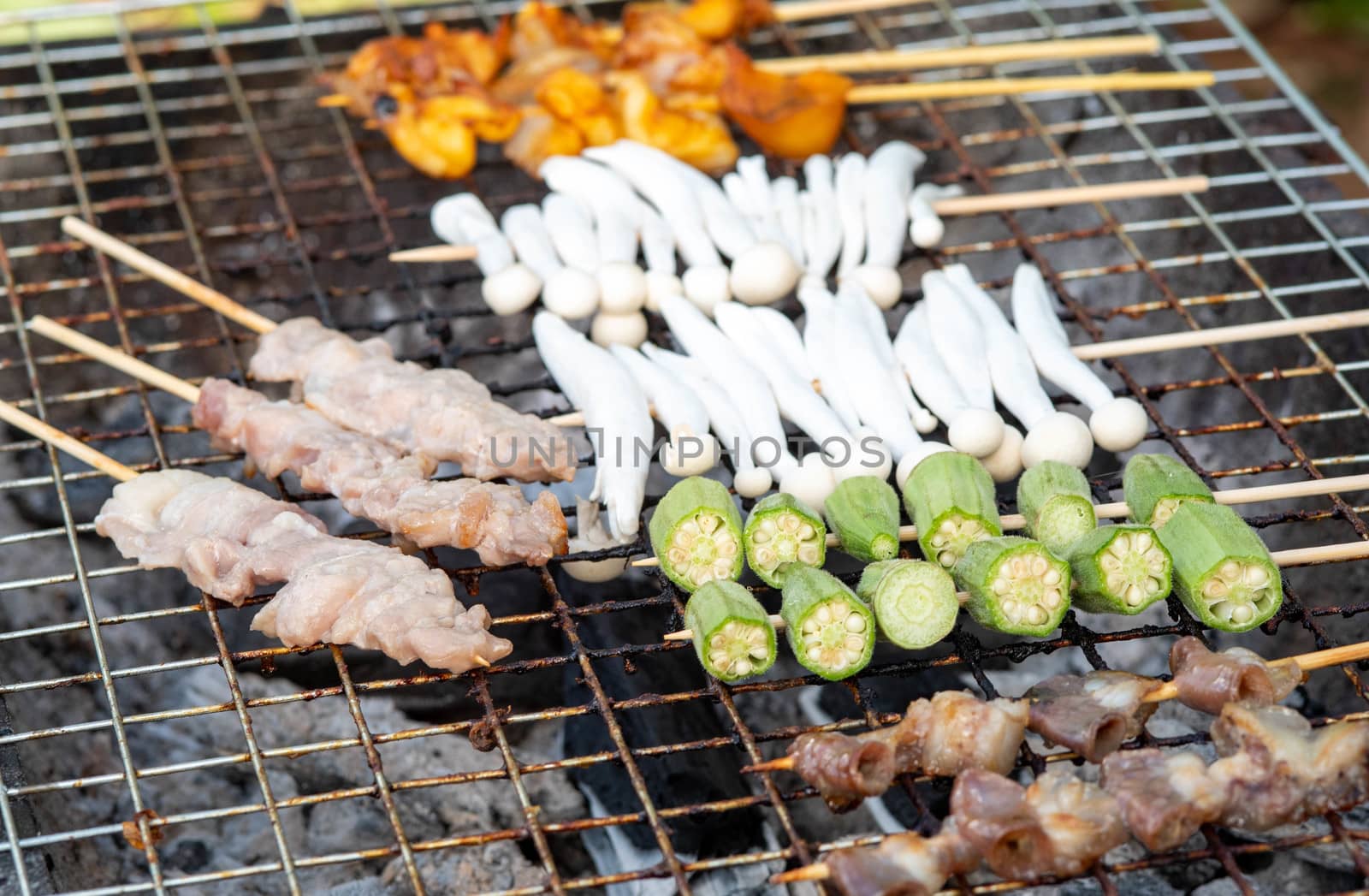 BBQ Yunnan Style as meat, squid, mushroom and pork waiting to be grilled in charcoal grill, eaten with seafood sauce or Chinese Hot Spicy Herb. Thai delicious street food in local market.