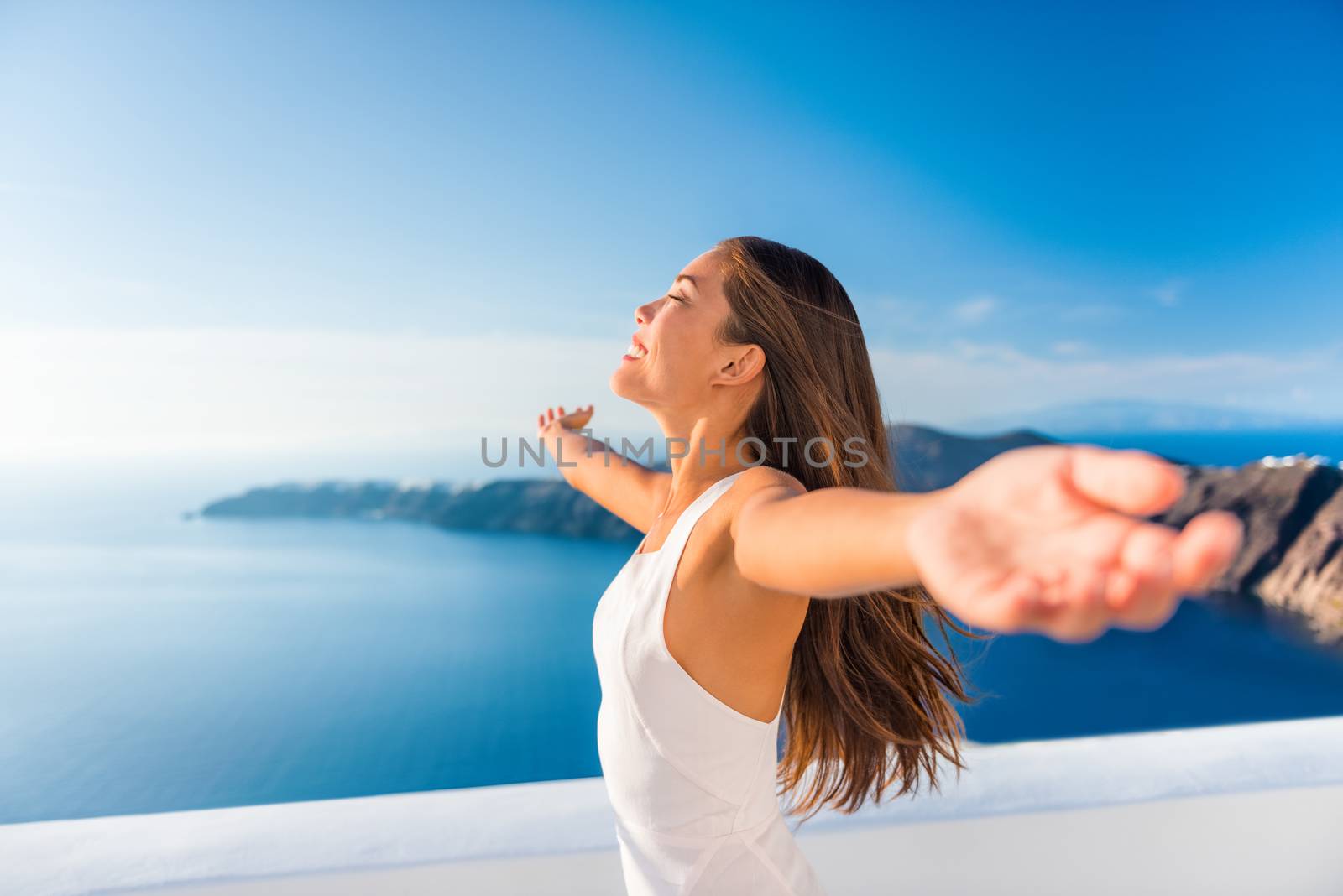 Europe cruise destination Santorini Greece travel vacation carefree woman enjoying freedom with open arms in famous travel holiday. Elegant Asian girl on greek travel luxury resort in Oia Santorini by Maridav