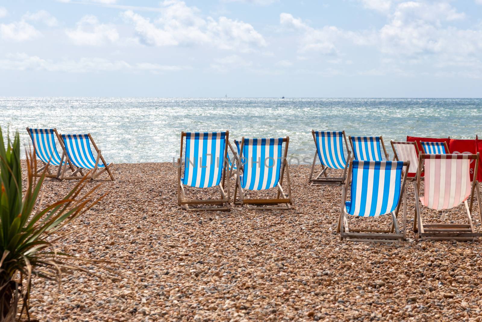 Colourful striped empty deck chairs on Brighton beach, England by magicbones
