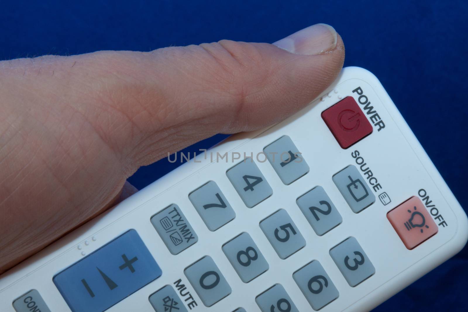 hand with a white remote control with multi-colored buttons by client111