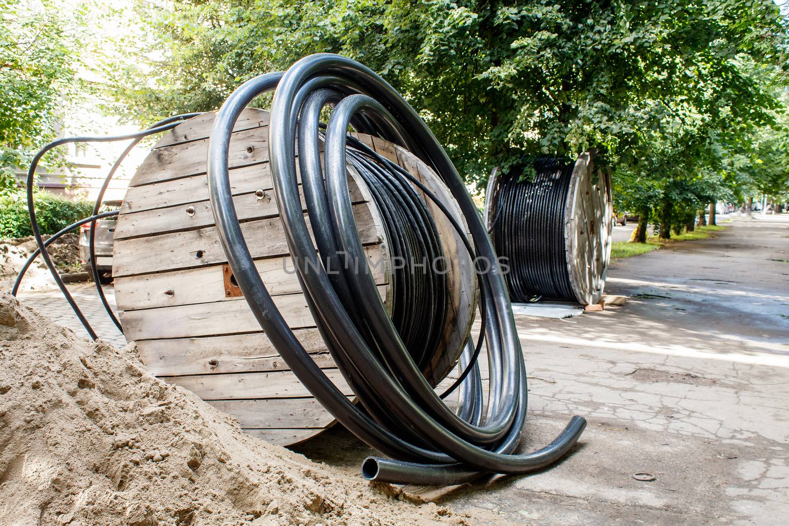 two large wooden industrial reels with cable in city street on sunny summer day