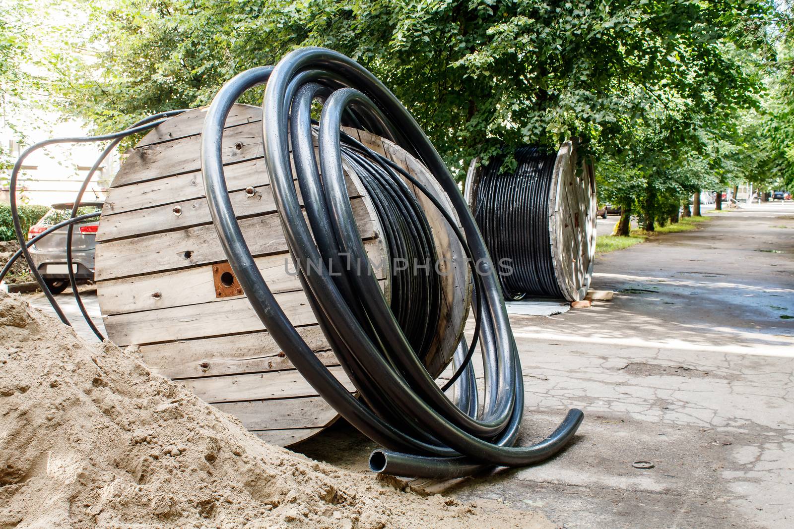 two large wooden industrial reels with cable in city street on sunny summer day