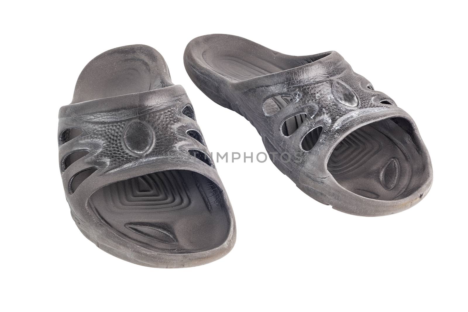pair of used cheap black soft rubber slippers with signs od friction wear isolated on white background.