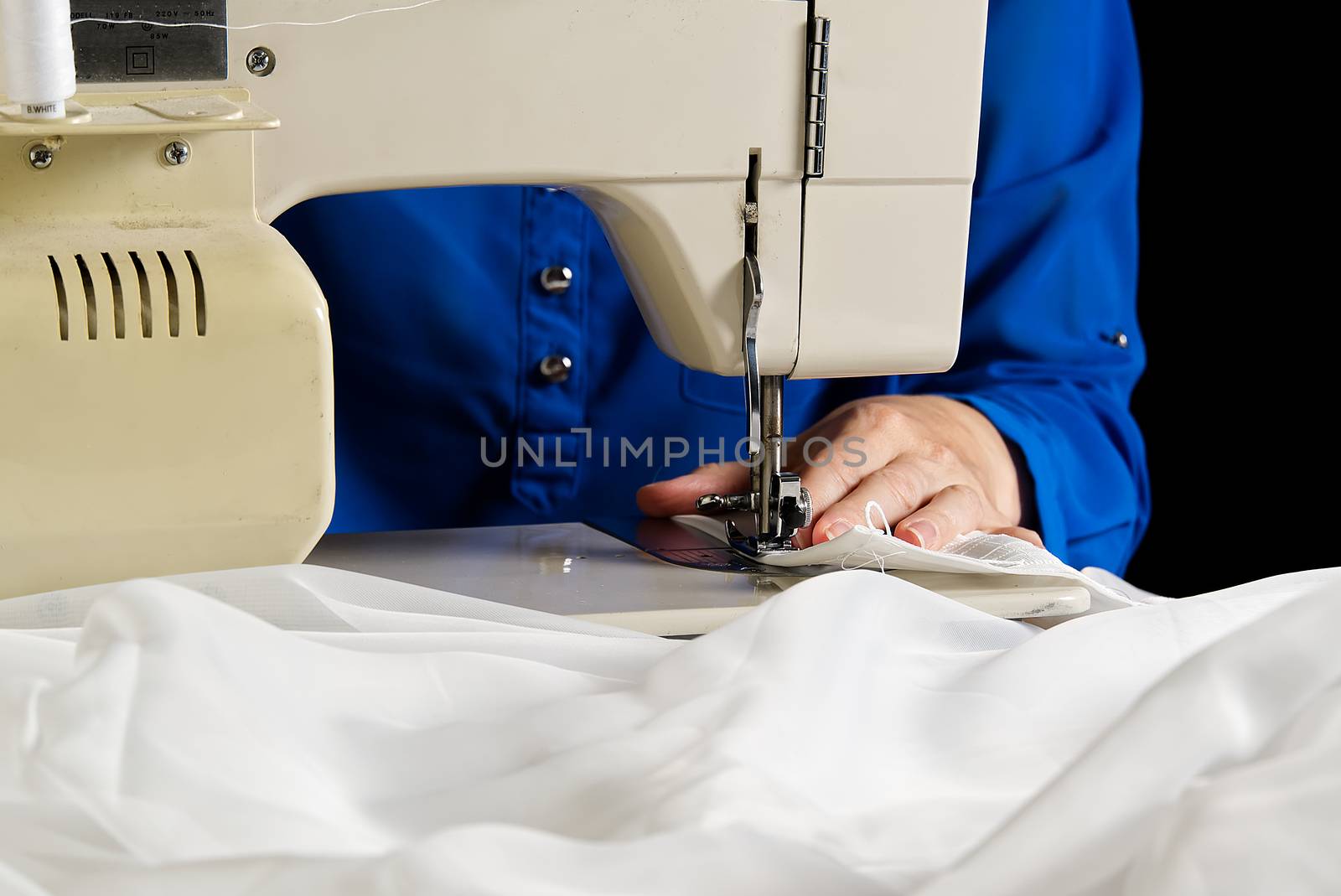 seamstress sews white curtains, close up view