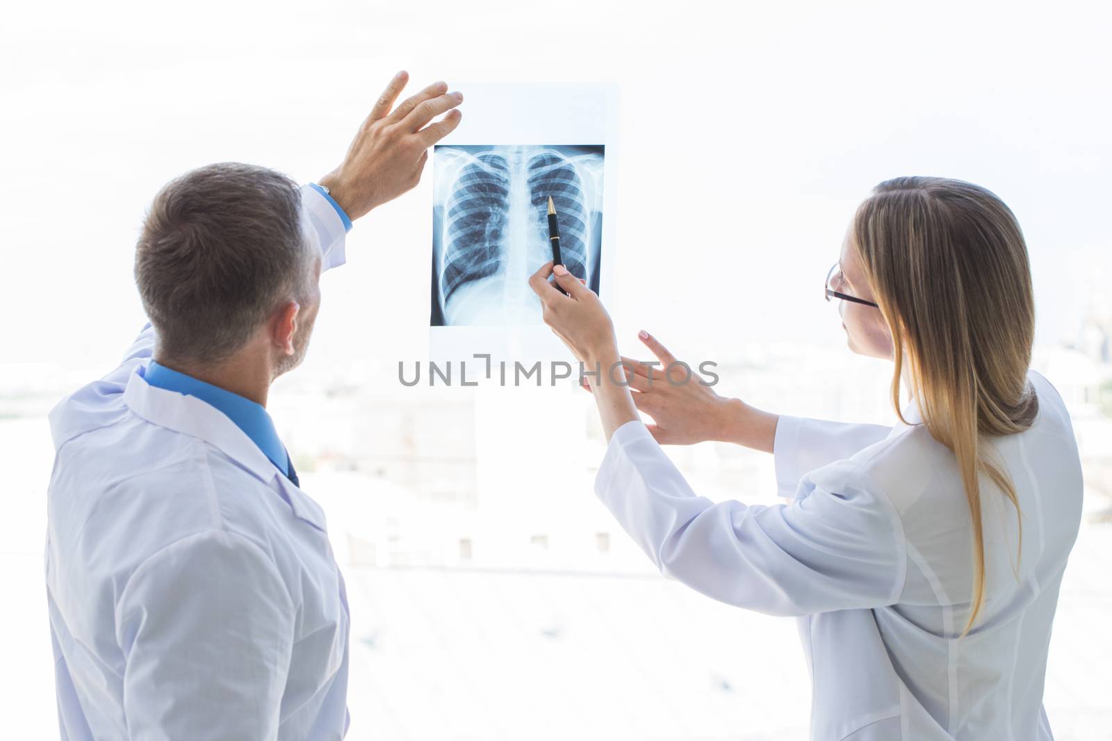 Two doctors examining a x-ray film by the window at clinical office