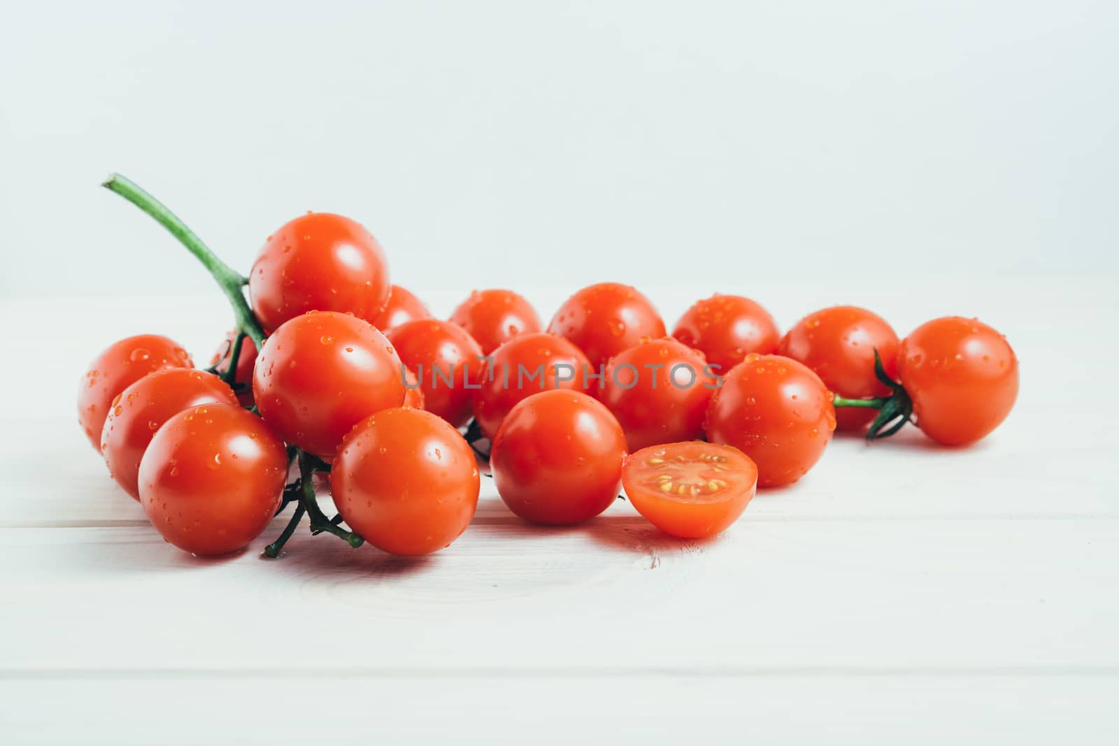 Cherry tomatoes on the white wooden table by andreonegin