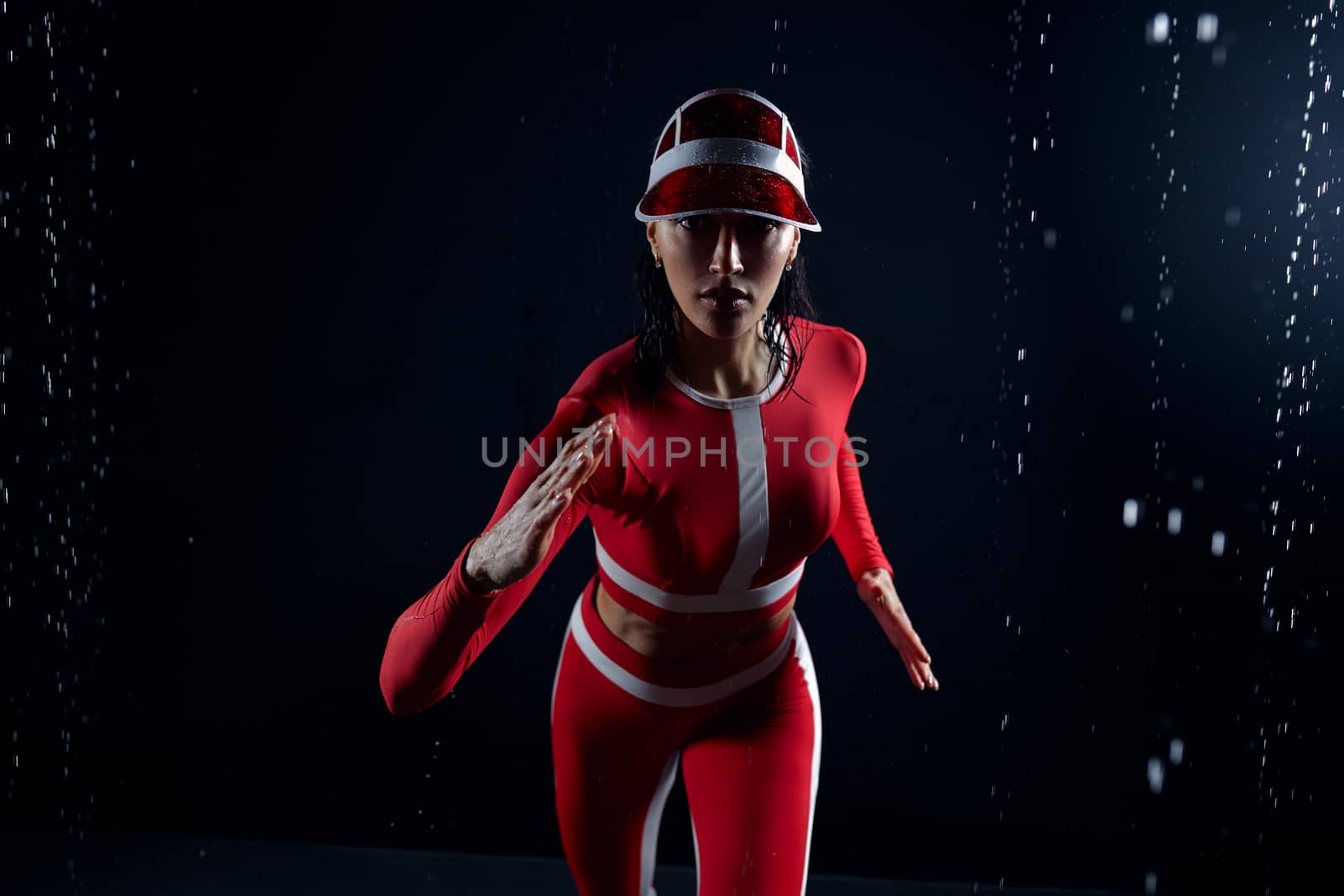 Beautiful young girl in sportswear in aqua studio. Drops of water spread about her fitness body. The perfect figure on the background of water splashes. Bad weather for sport
