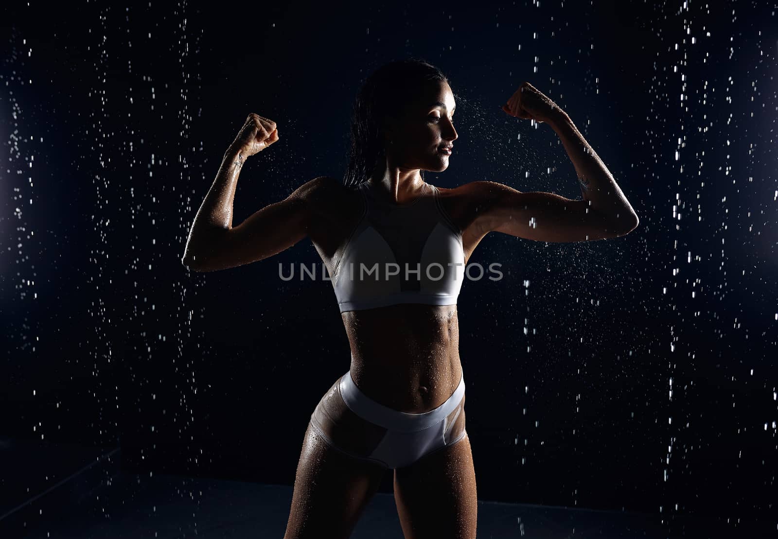 Beautiful athletic caucasian girl with a perfect figure is standing under the water. Fitness woman in a spray of water. Sports freshness. concept by andreonegin
