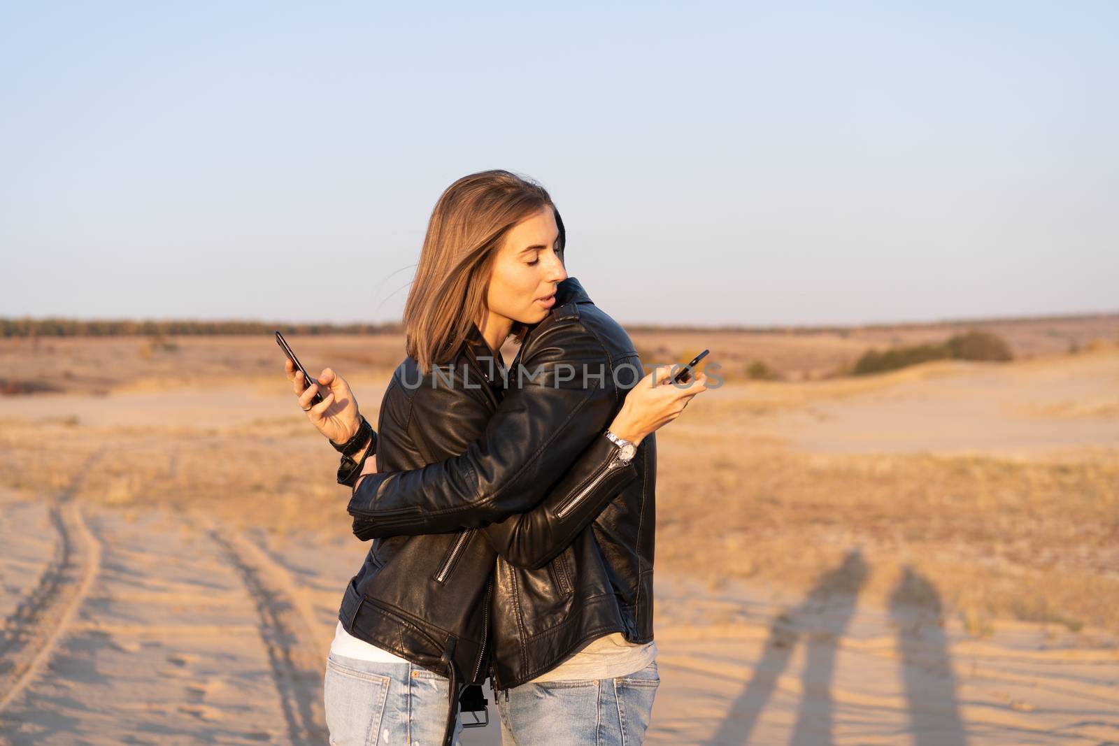 Happy and cute adorable adult couple leather jacket and jeans man with woman girlfriend walking Concept about how mobile phones social networks and the Internet affects the relationship between people