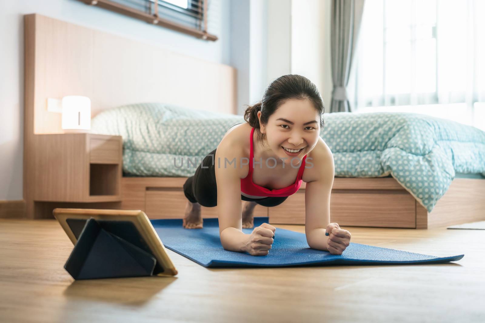 Asian woman practicing yoga from home with laptop when Covid19 outbreak and lockdown, healthy or Meditation Exercise, workout at home, coronavirus pandemic and quarantine,sports and healthcare concept