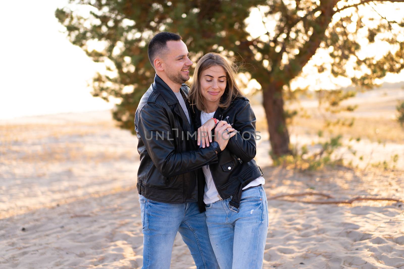 Happy and cute adorable adult couple leather jacket and jeans man with woman girlfriend walking, have fun play, laugh,smile and jump on sunset at desert crazy in love, emotions and relationship