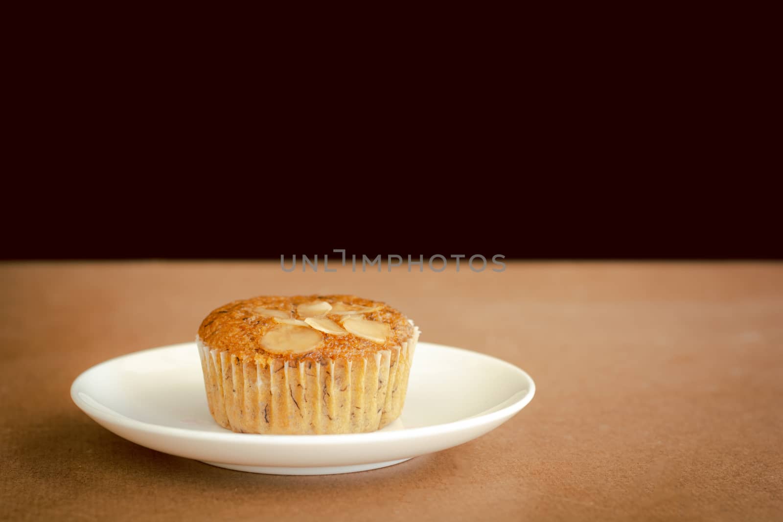 Delicious banana cup cake on white dish and wooden table with copy space. Homemade bakery.