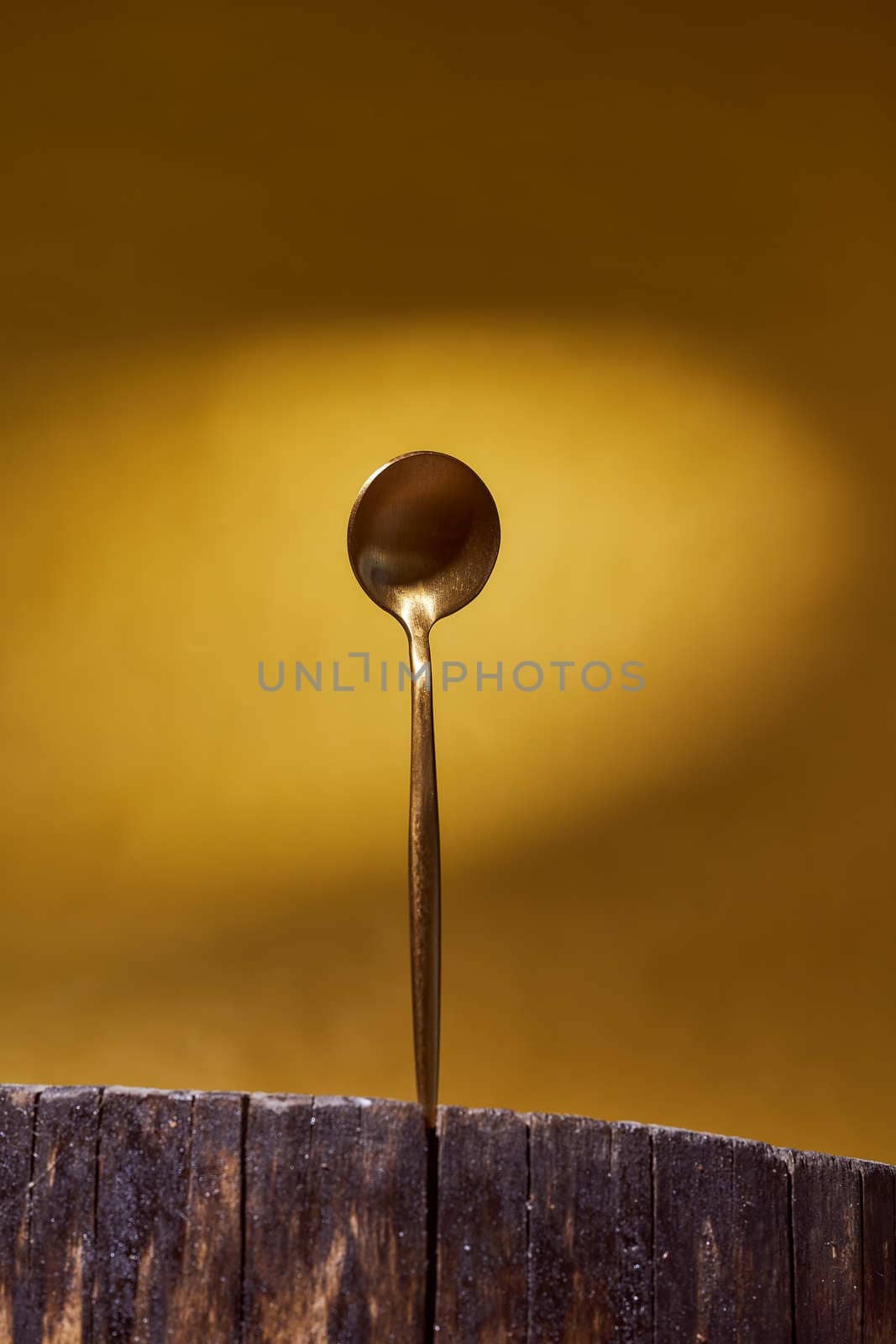 Golden Spoon standing on wooden frame. yellow background. High quality photo