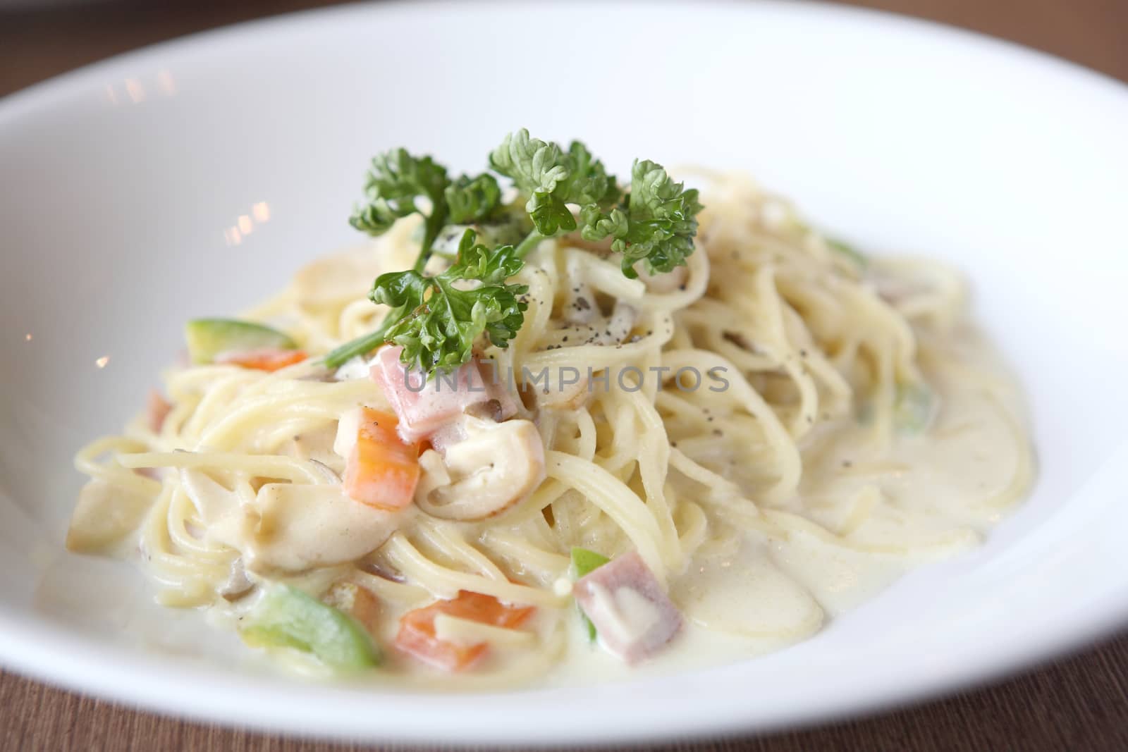 Spaghetti with mushroom and ham white sauce on wood background