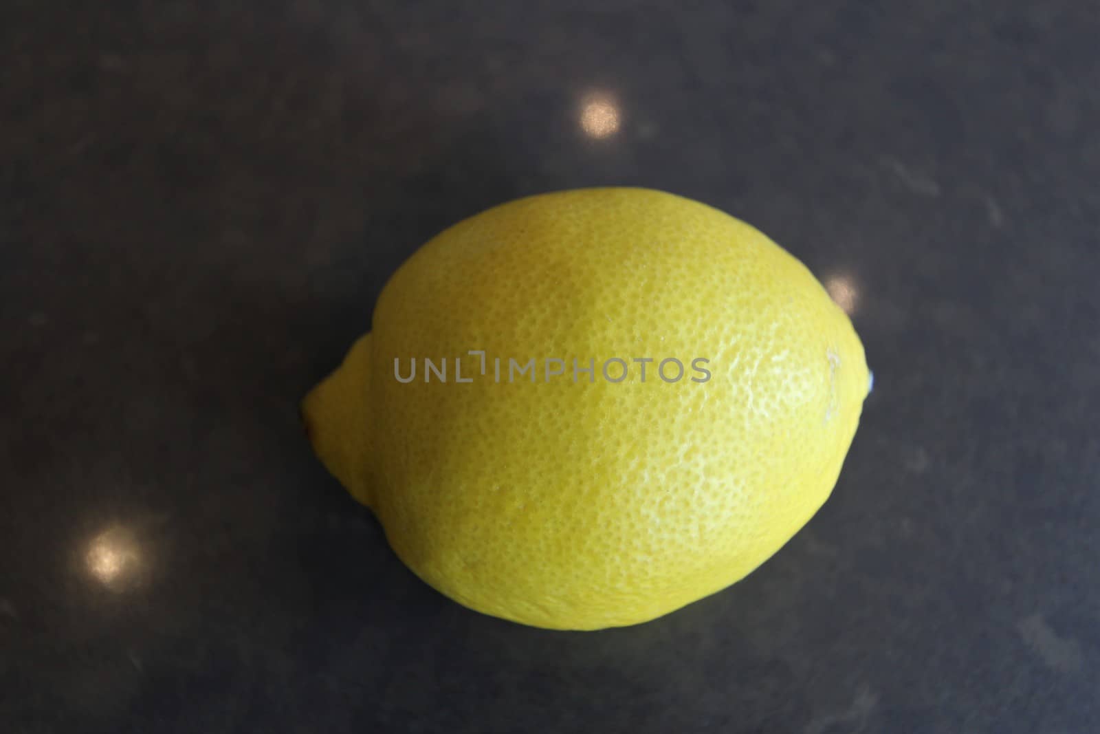 a whole yellow lemon on a gray stone surface