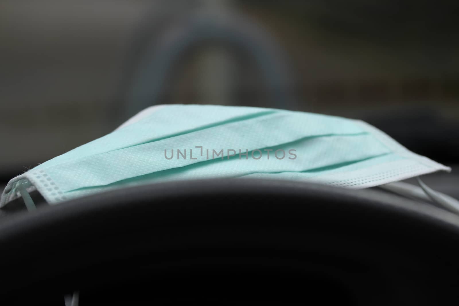 Green medical mask on the dashboard in the car