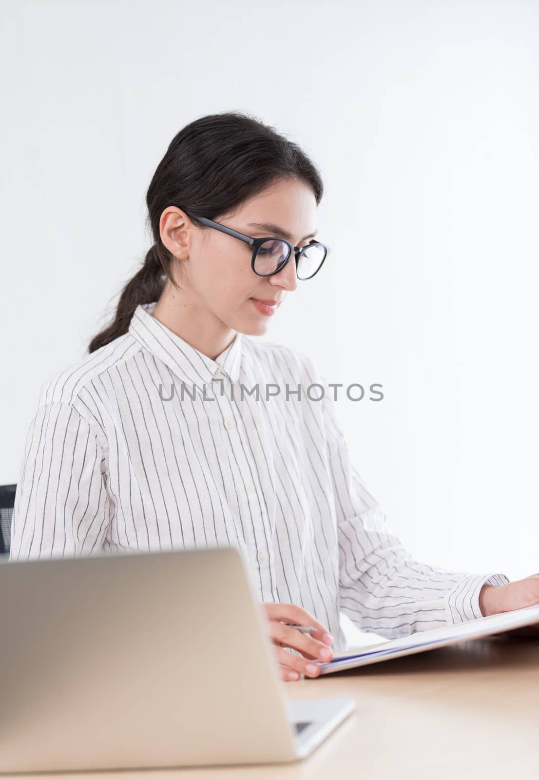 A businesswoman wearing glasses working with smiling and happiness at the office.