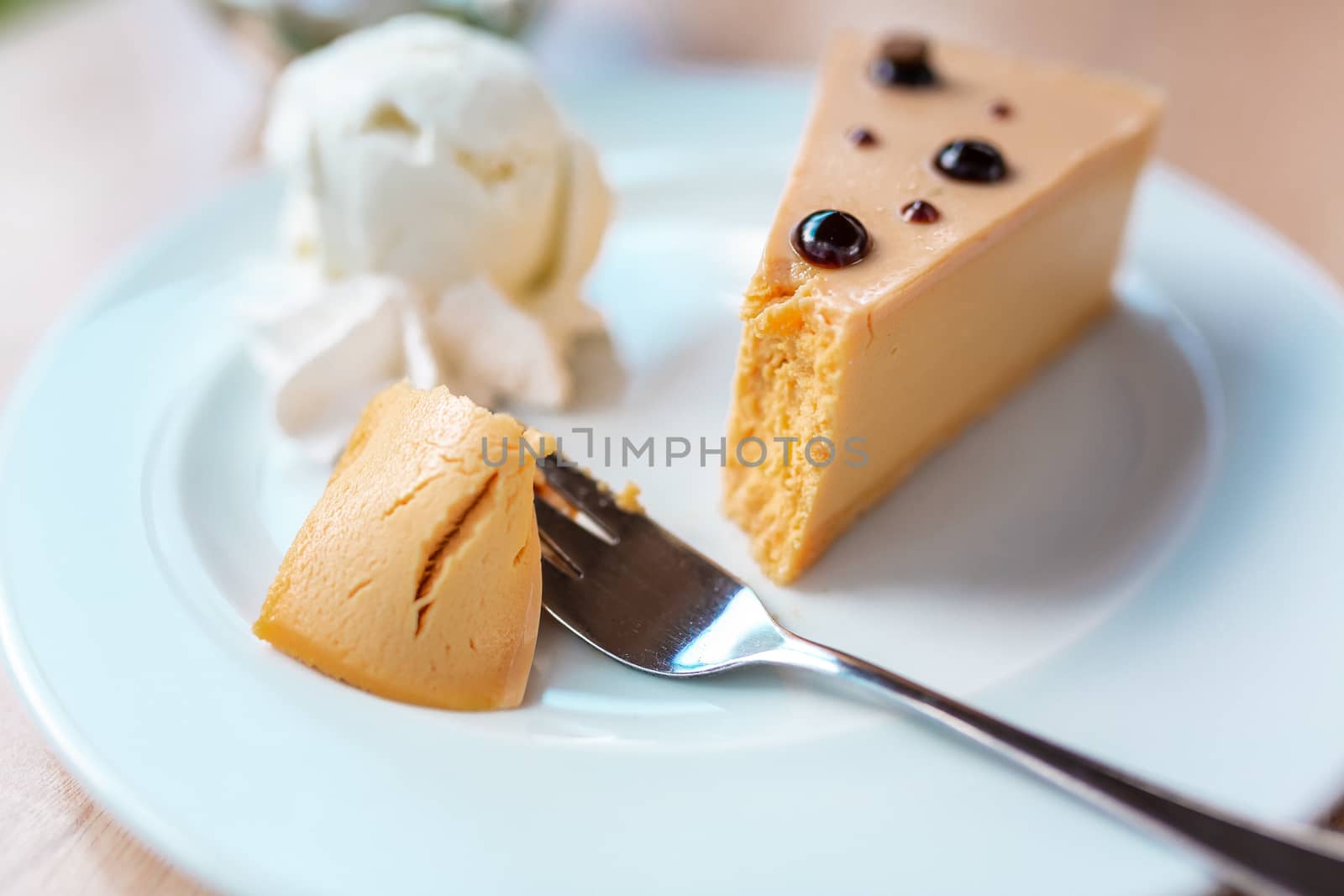 A piece of delicious caramel cheesecake served with ice cream and flowers on the table