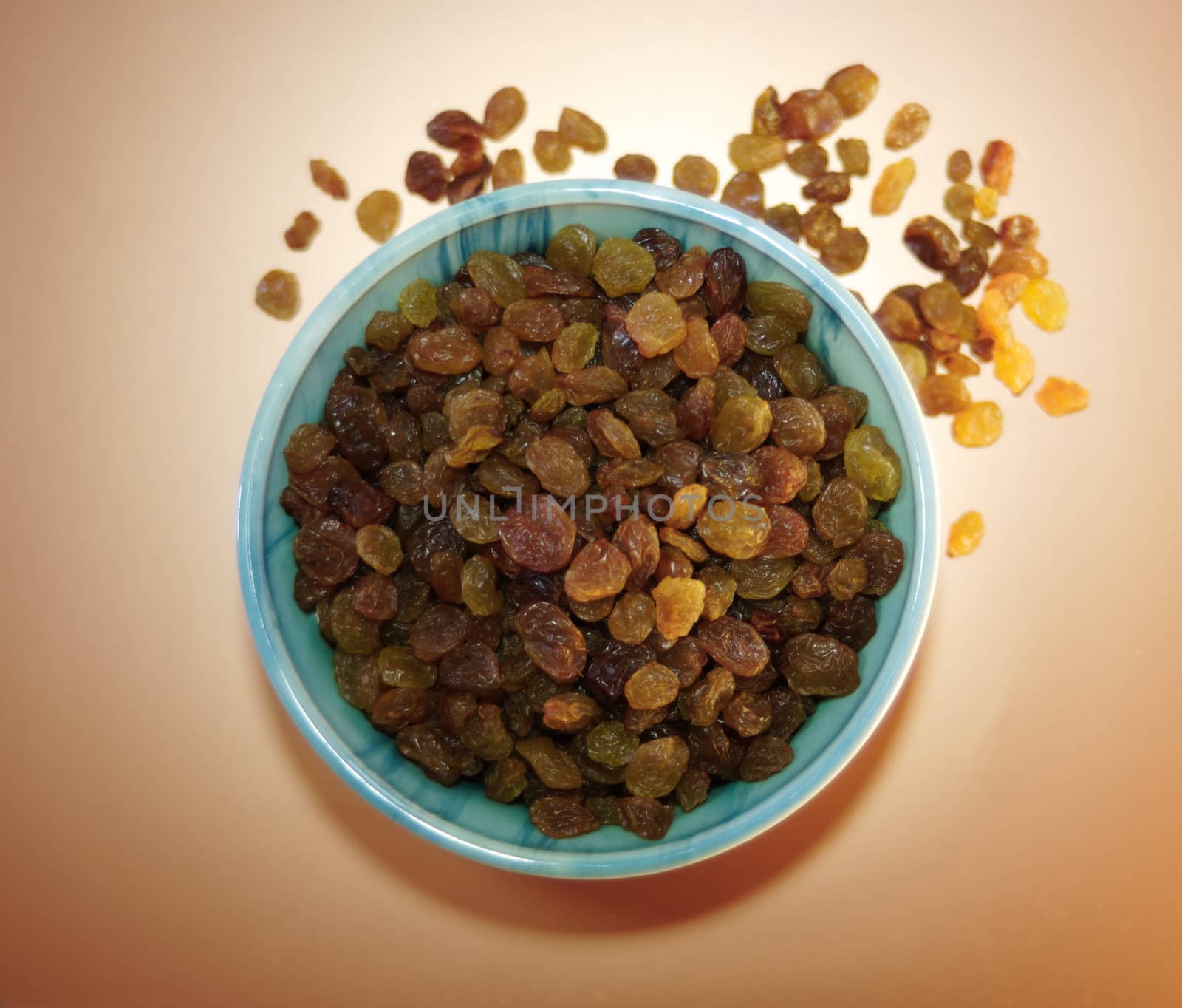 top view of a green plate with appetizing raisins on a light background