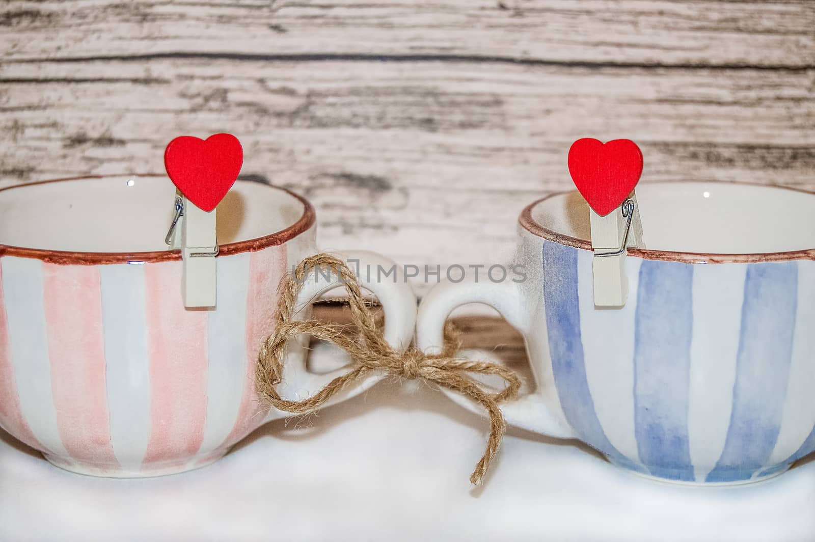 A pair of cups with clothespins and hearts tied with twine. the concept of a strong family, a nice home.