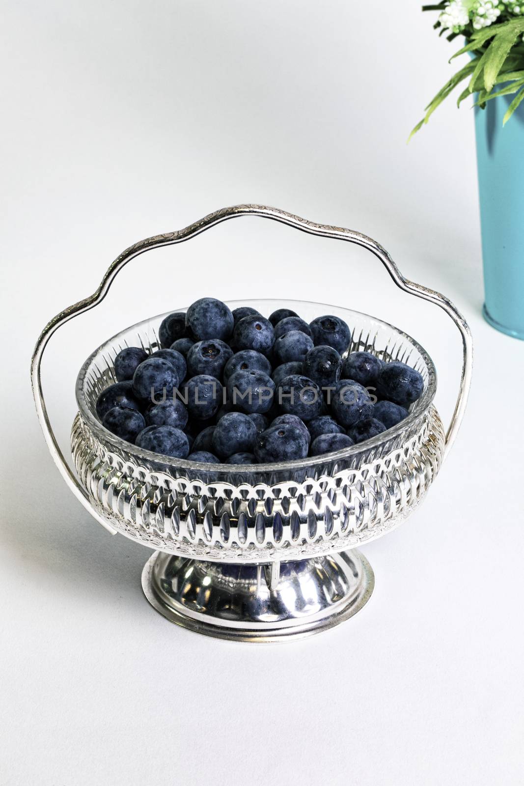 Plump, ripe blueberries in antique silver filigree bowl.