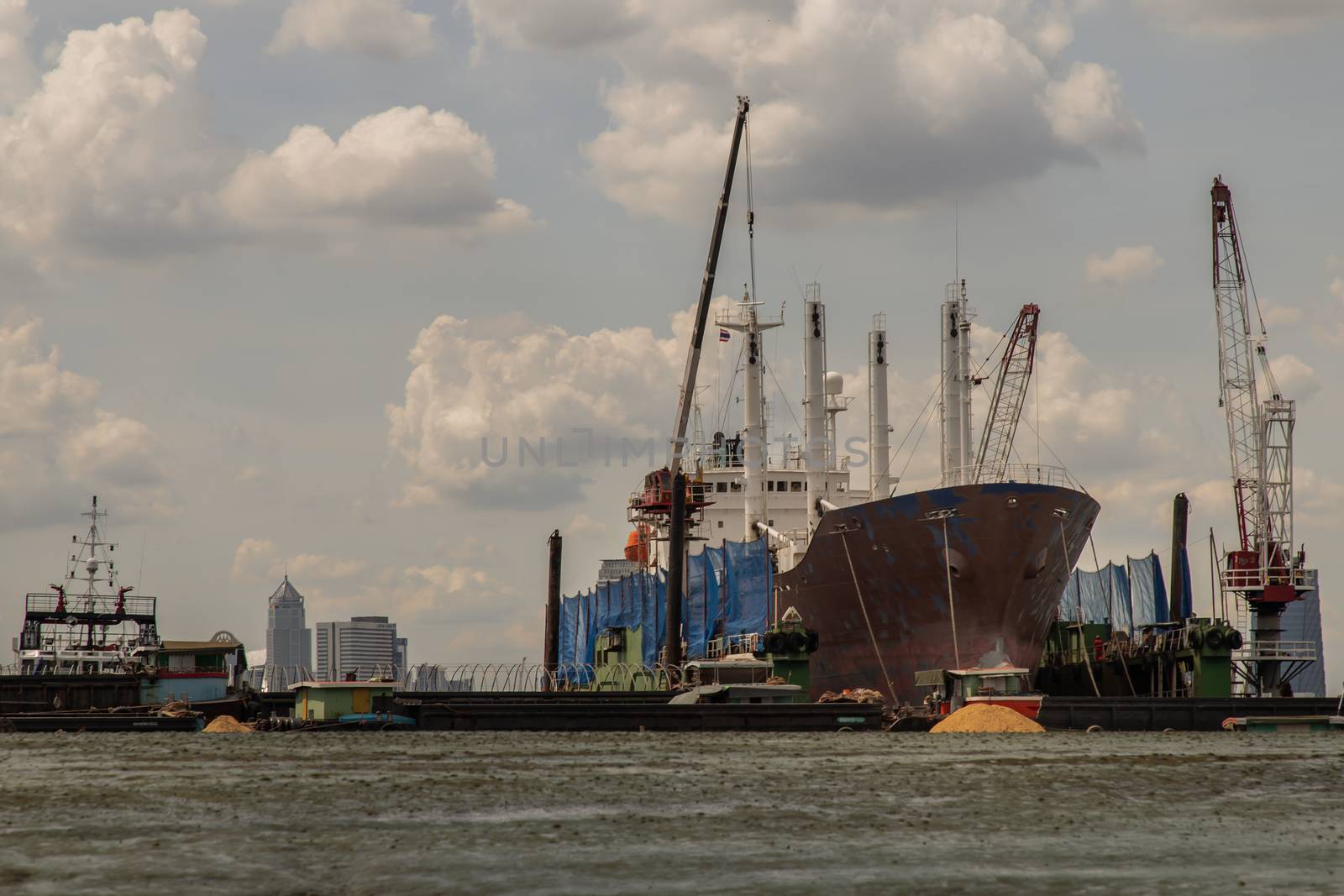 Bangkok, Thailand - 10 Jul 2020 : Cargo ship parked in the middle of the Chao Phraya River and Dramatic sky background.