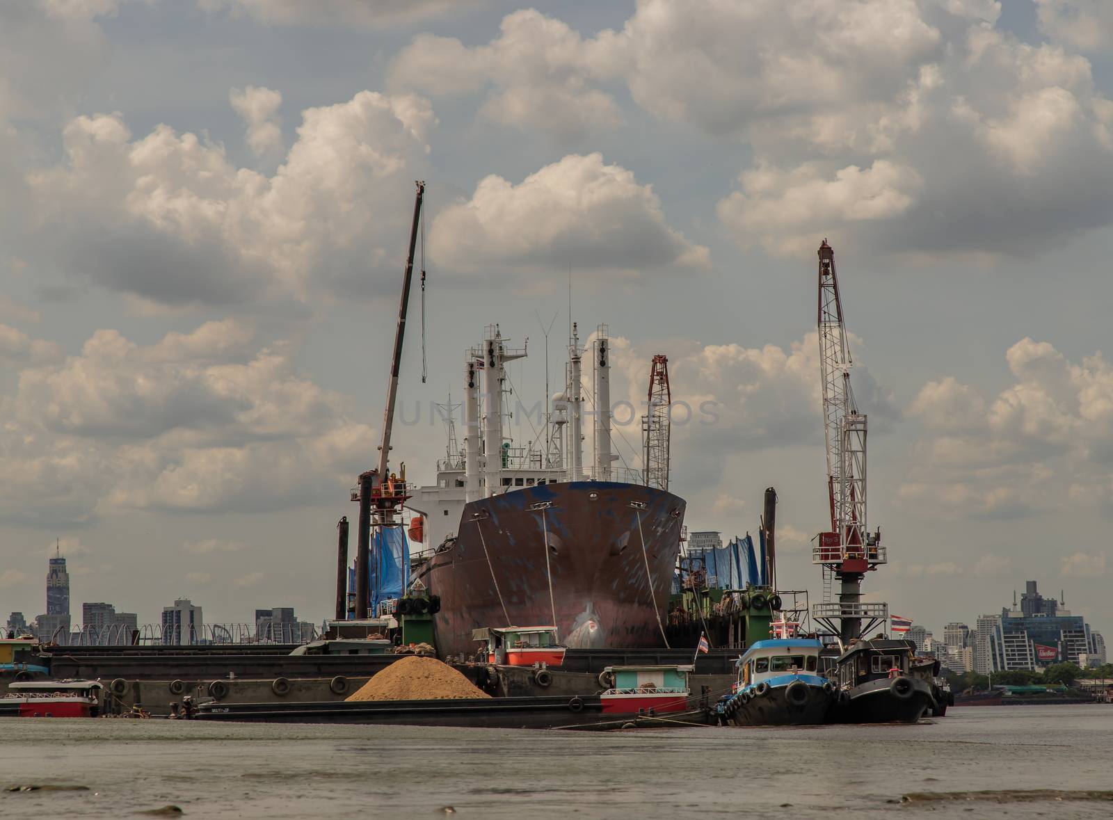 Bangkok, Thailand - 10 Jul 2020 : Cargo ship parked in the middle of the Chao Phraya River and Dramatic sky background.