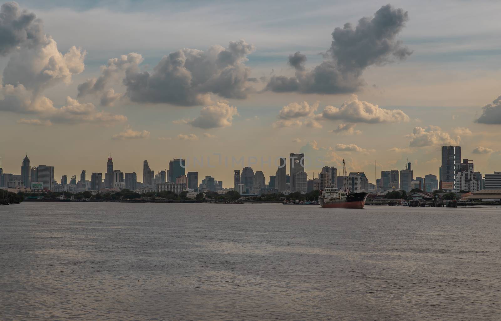 Bangkok, Thailand - 10 Jul 2020 : A cargo ship parked in the middle of the Chao Phraya River with city at the background.