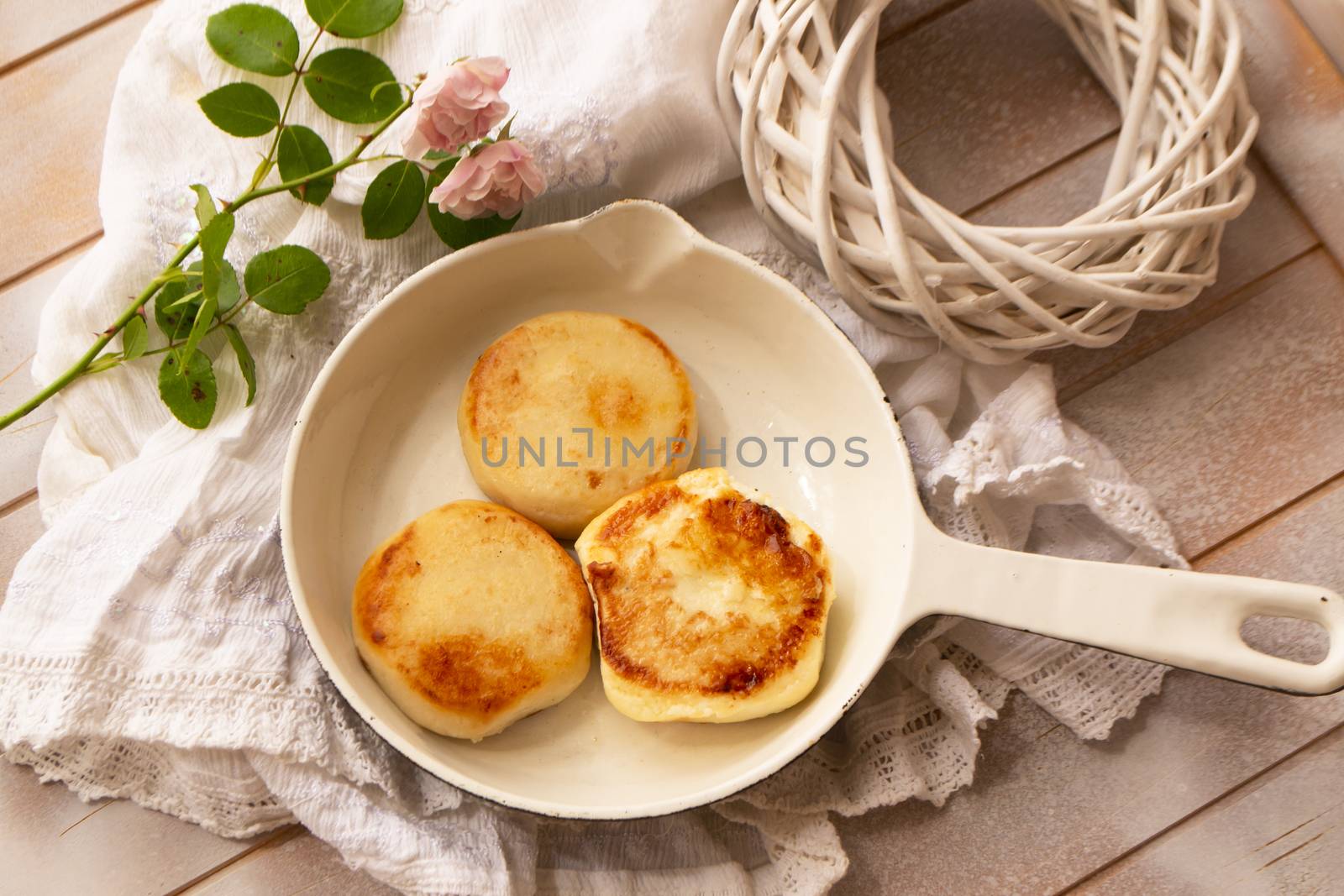 Cast-iron frying pan with curd pancakes or syrniki, shabby table, flat lay
