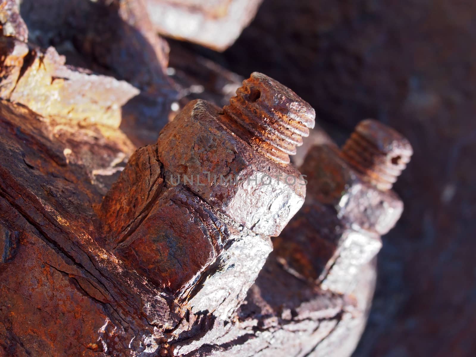 a close up of brown rusted threaded bolts and nuts on old corroded machinery
