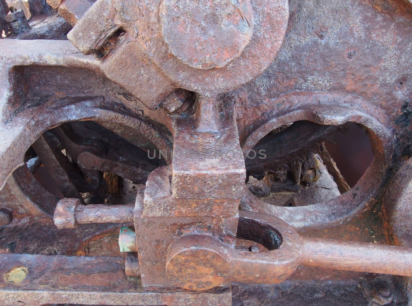 a close up of an axle and rods on old rusted abandoned industrial machinery