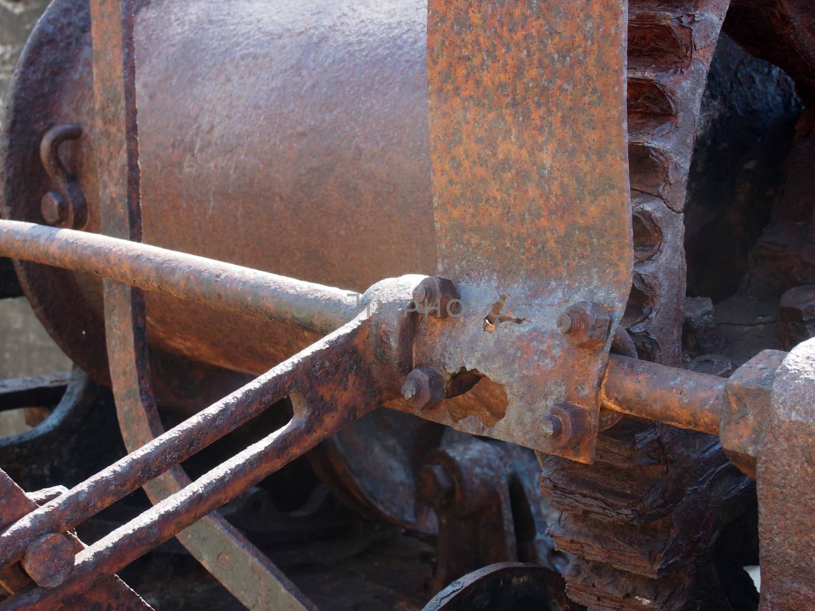 a close up of rusted cogs bolts and gears on an old broken industrial winching machine