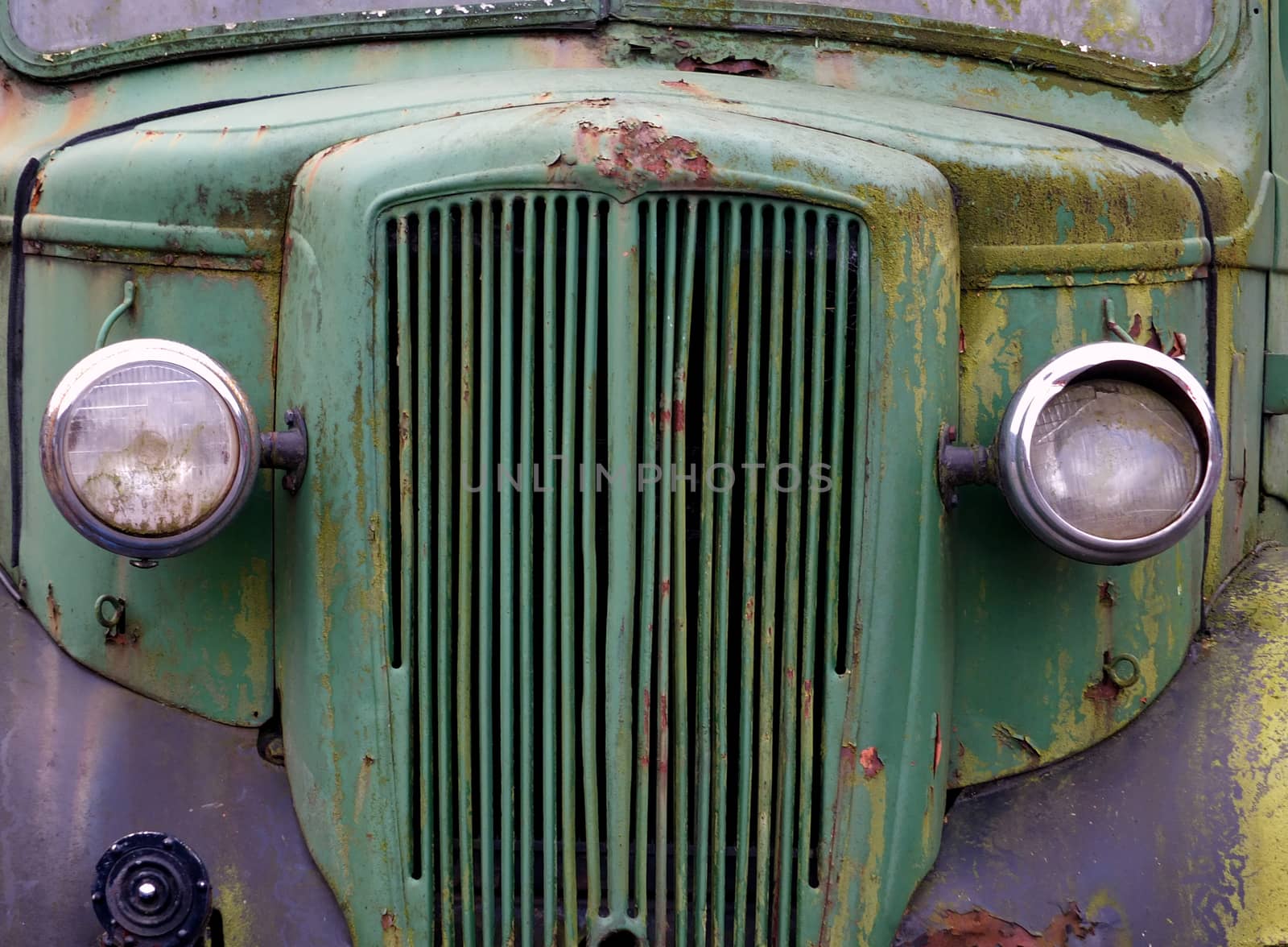 close up of the front of an old abandoned rusting green truck co by philopenshaw