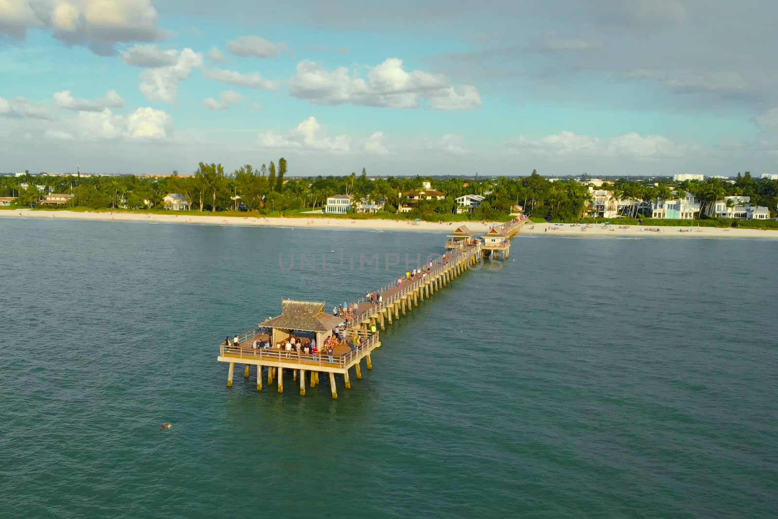 Drone flies around a fishing pier in Naples, Florida USA. Drone flies near a pier in Naples, Florida at sunset time, aerial view. Naples, Florida is a tourist town in the USA, Aerial view photo.