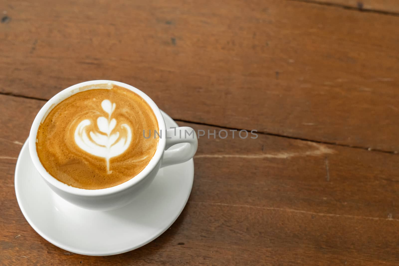 Hot coffee with late art on wooden table