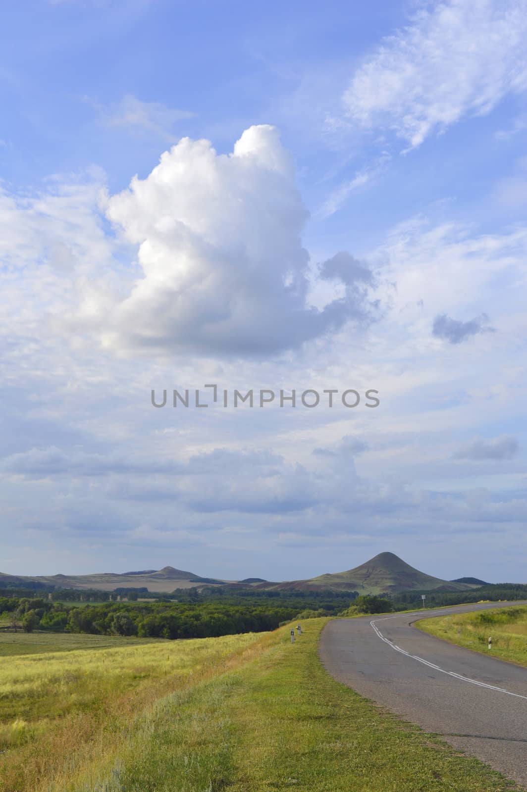 summer landscape with road, mountain and blue sky with clouds
