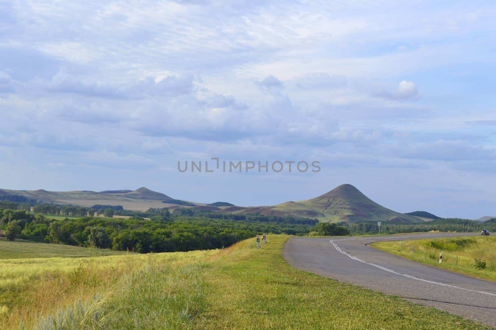 summer landscape with road, mountain and blue sky with clouds