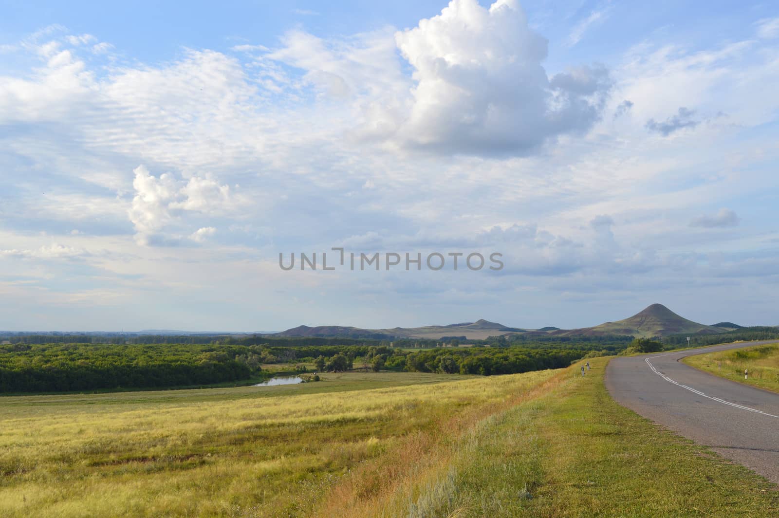 summer landscape with road, mountain and blue sky with clouds