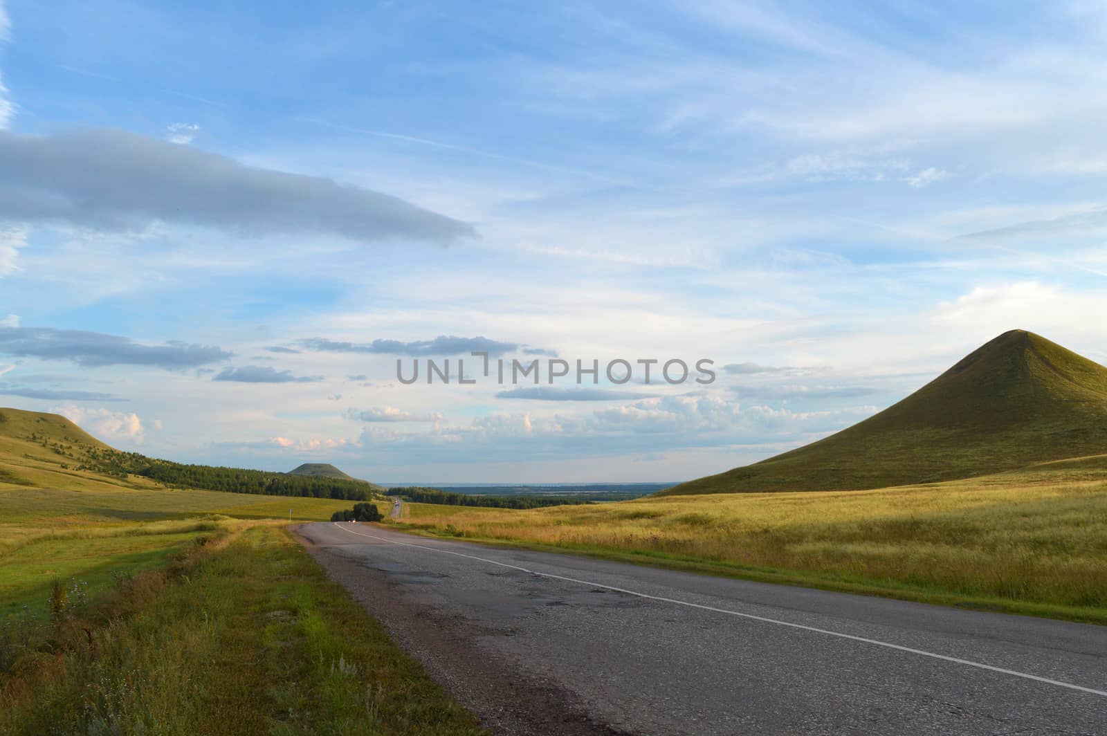 summer landscape with road, mountain and blue sky with clouds